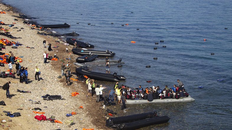 refugees-and-migrants-arrive-on-a-overcrowded-dinghy-on-a-beach-full-of-abandoned-dinghies-and-lifejackets-on-the-greek-island-of-lesbos-after-crossing-a-part-of-the-aegean-sea-from-the-turkish-coas